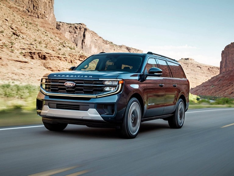 2025 Ford Expedition® Platinum MAX model driving down a mountain-lined road