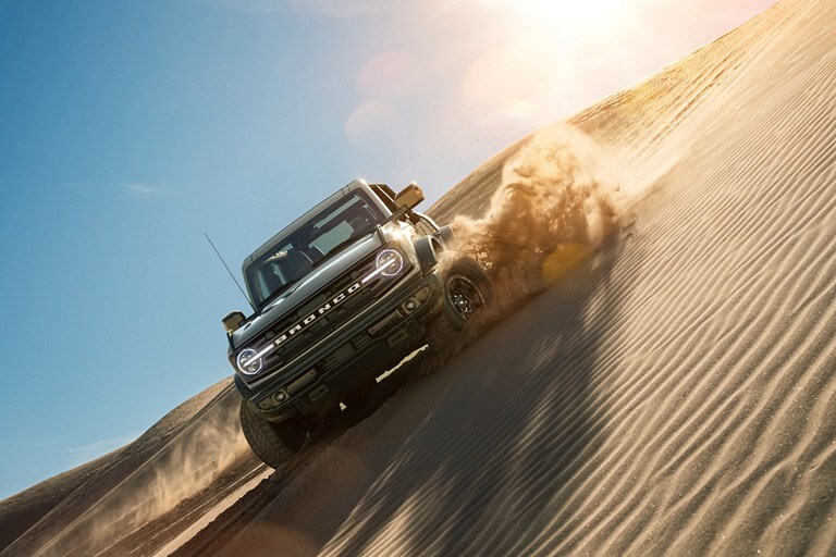A 2021 Ford Bronco driving over a sand dune