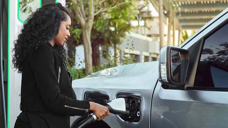 A woman plugs a charger into her Ford vehicle