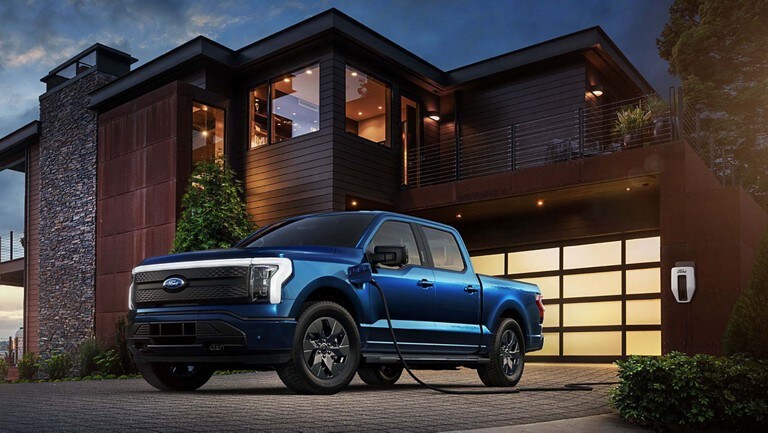 A 2023 Ford F-150® Lightning® parked in a driveway and plugged-in