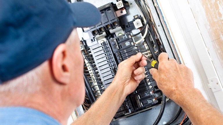 A technician wires a breaker panel