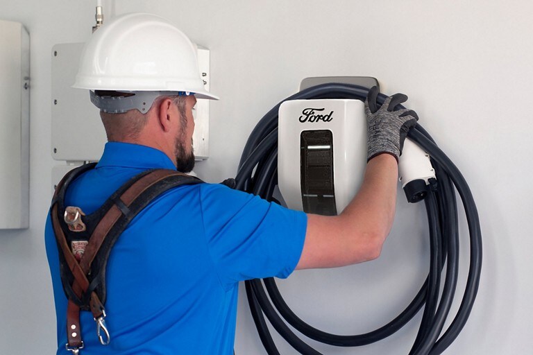 A technician installs a Ford Charge Station pro on a wall