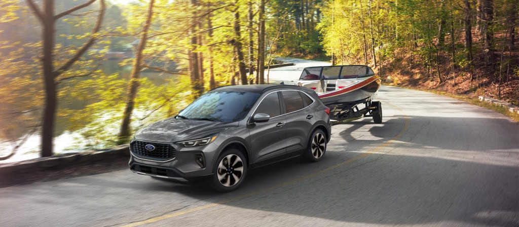 2025 Ford Escape® SUV with 2.0L EcoBoost® engine towing a boat on a tree-lined road