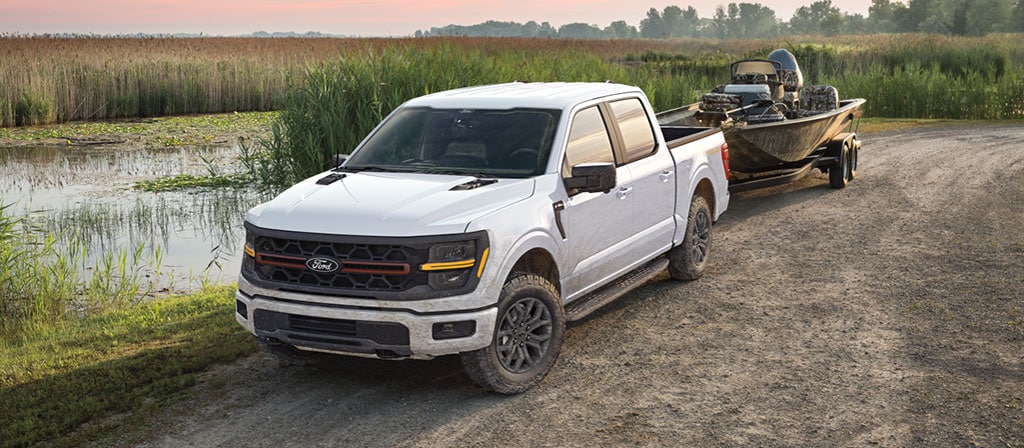 2025 Ford F-150® pickup towing a fishing boat near a small secluded lake