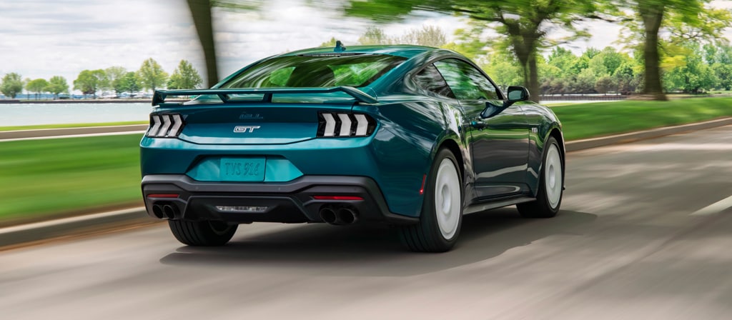 Rear view of a 2026 Ford Mustang® GT Premium fastback with the available FX Package being driven near a lake