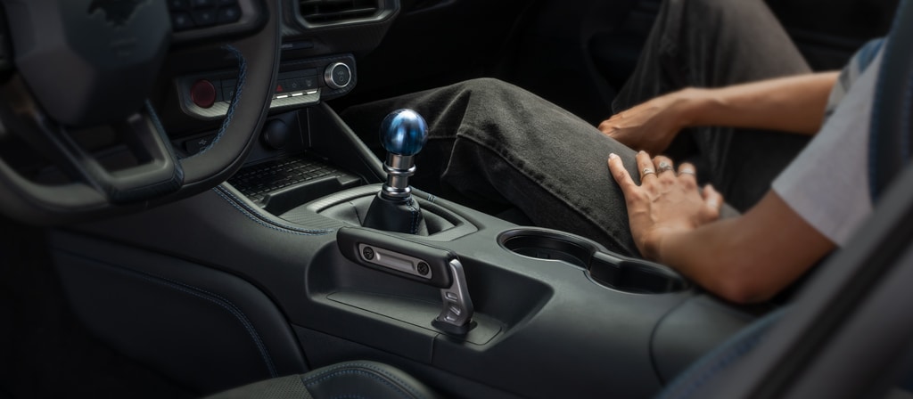 Person sitting in a 2026 Ford Mustang Dark Horse® fastback with unique titanium Anodized Blue shift knob