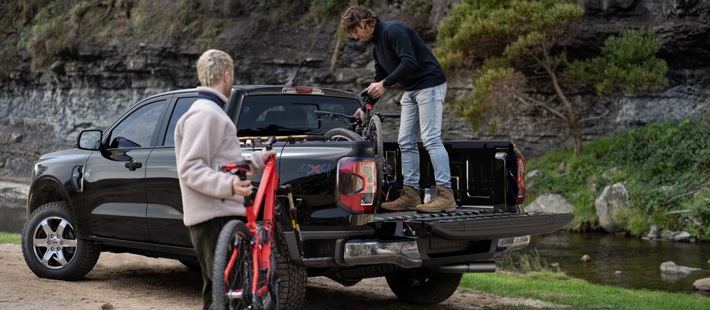 Two people loading gear into the bed of a black 2025 Ford Ranger® pickup