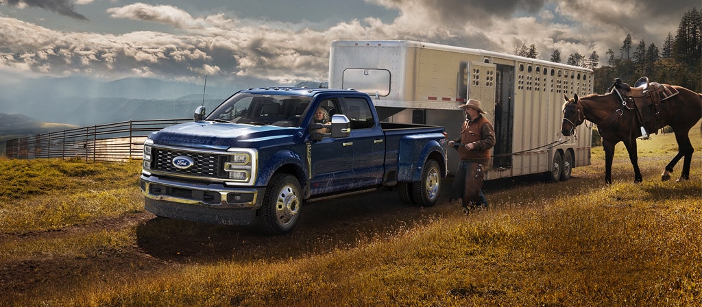 2026 Ford Super Duty® F-450® King Ranch® model in Argon Blue towing a horse carrier on a grassy farm