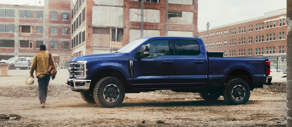 A person walking away from their 2026 Ford Super Duty® F-250® Lariat® model in Argon Blue on a construction site