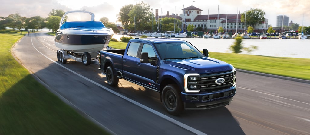 2026 Ford Super Duty® F-350® Platinum® model in Argon Blue towing a speed boat on a paved road