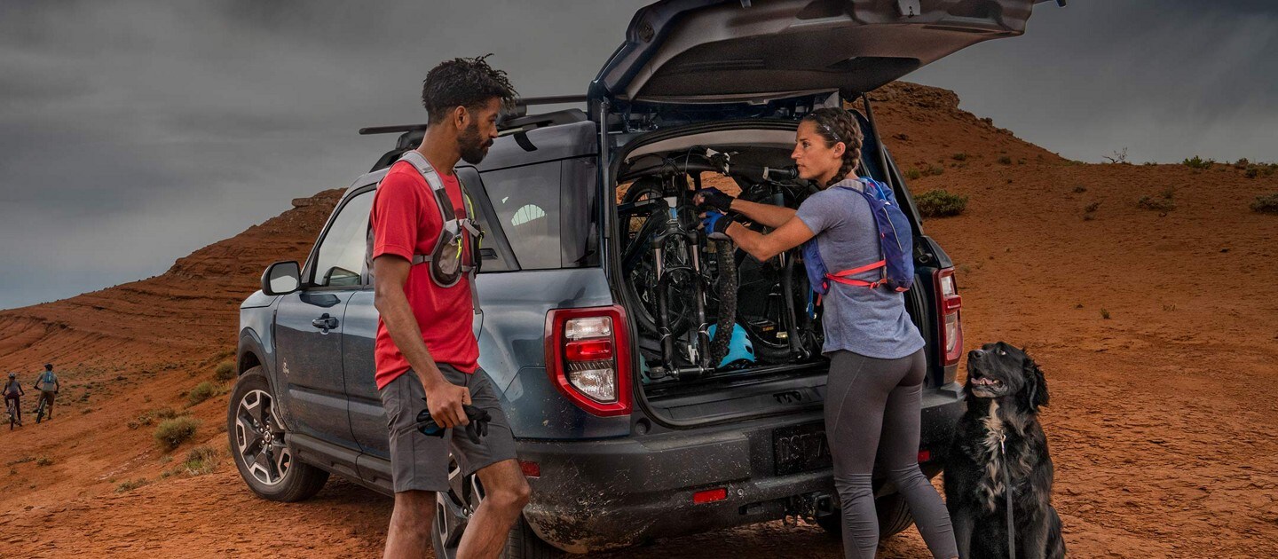 Two people standing near the back of the vehicle