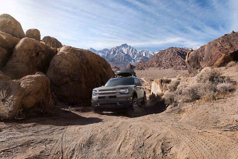 2023 Ford Bronco® Sport SUV being driven through a dirt trail with mountains in the distance