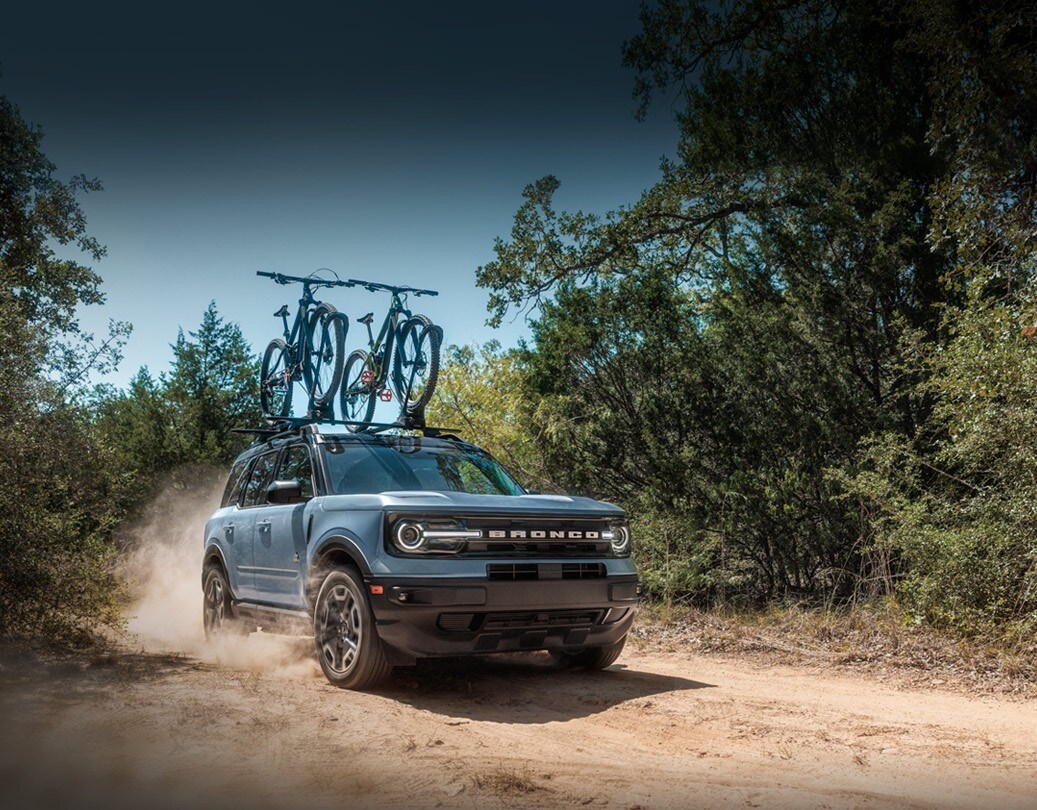 2024 Ford Bronco® Sport SUV being driven on dirt trail with bikes on the roof