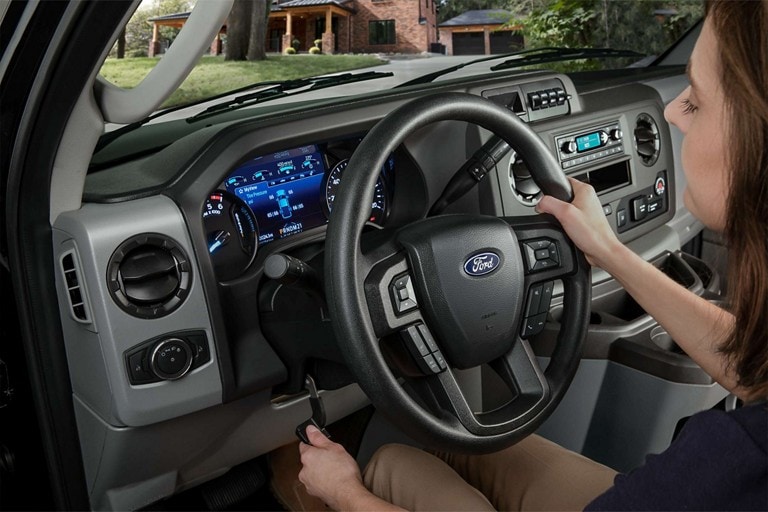 A person adjusting the steering column and steering wheel in a 2026 Ford E-Series Stripped Chassis