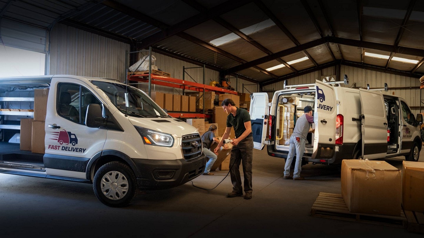 Two 2024 Ford E-Transit™ vans parked in a warehouse with people working out of them