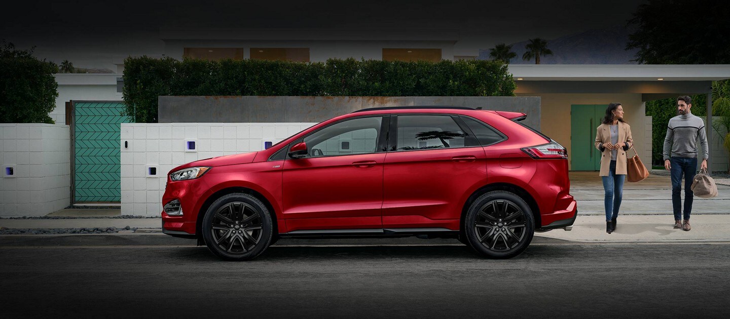 2023 Ford Edge® ST-Line model in Rapid Red parked in front of a modern home with a man and woman approaching