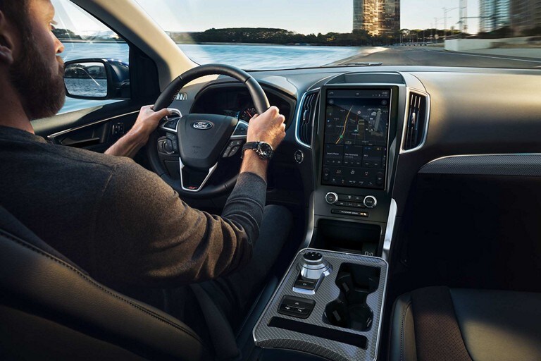 Close-up of a man driving a 2023 Ford Edge® with hands on the heated steering wheel