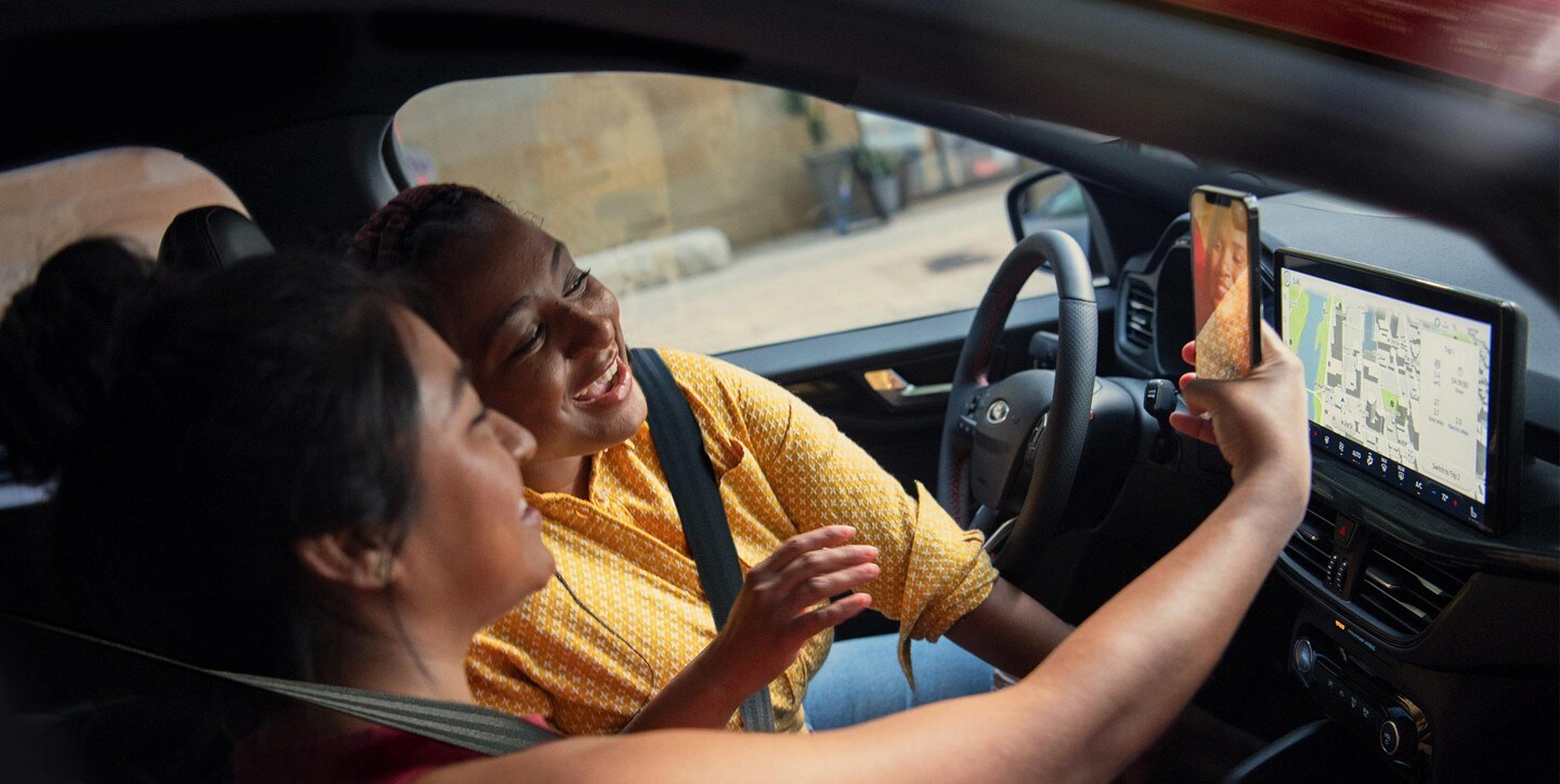 Close-up of interior of a 2023 Ford Escape® as people look at their smartphone