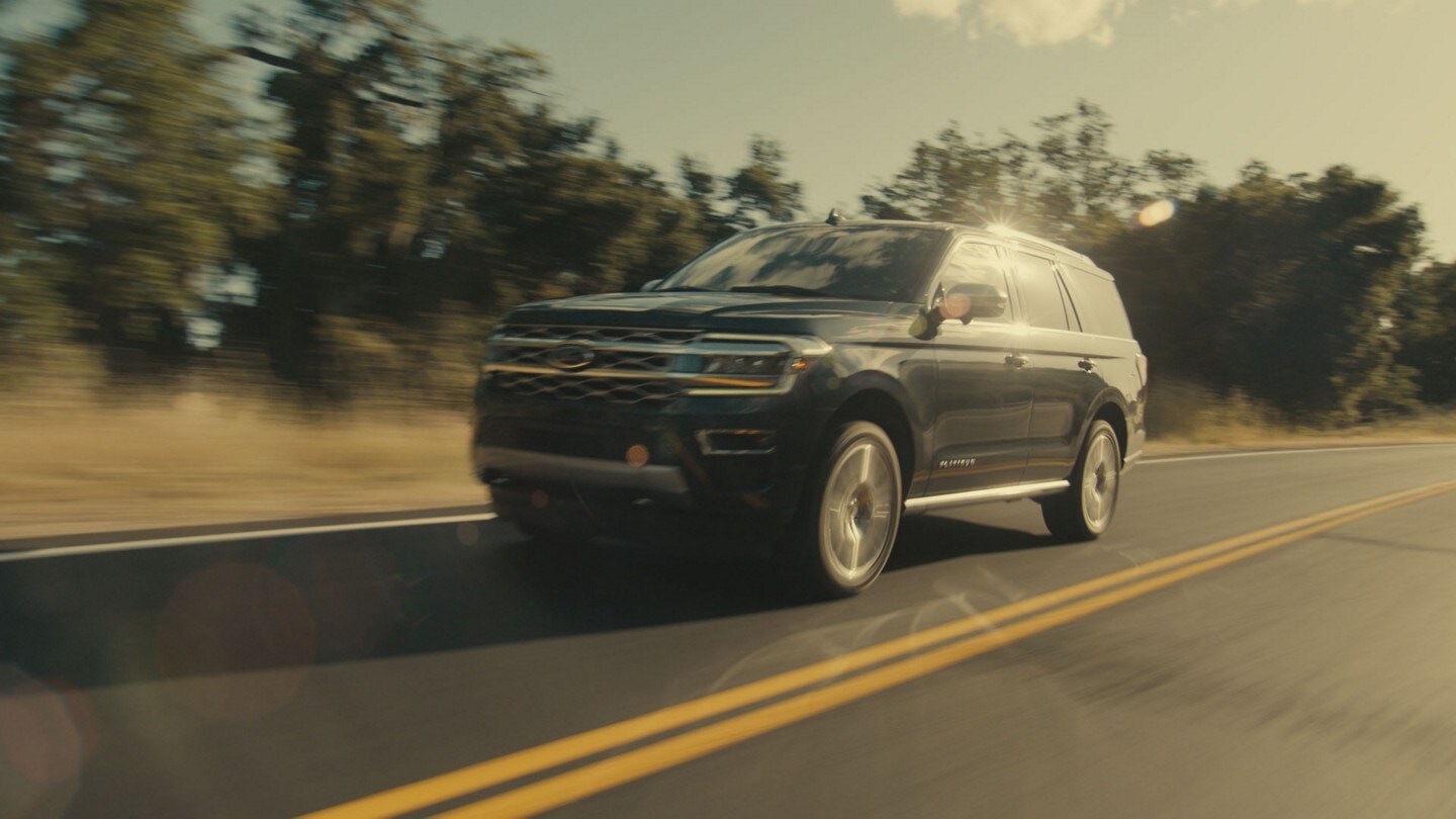 A black 2023 Ford Expedition travels along a two lane highway.