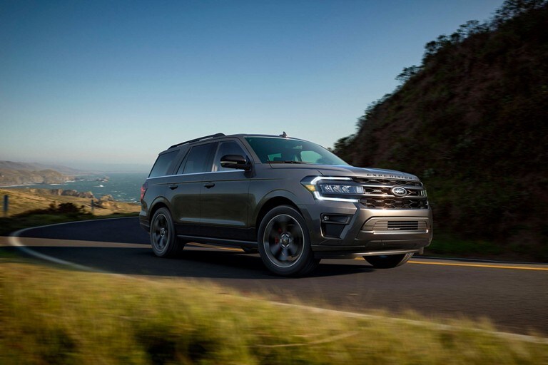 A 2023 Ford Expedition on a curving road with the ocean behind it