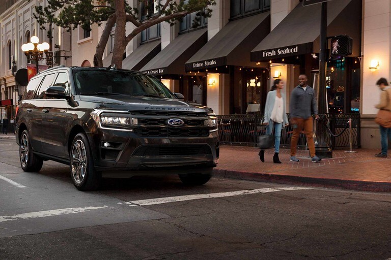 A 2023 Ford Expedition parked in front of a restaurant at dusk