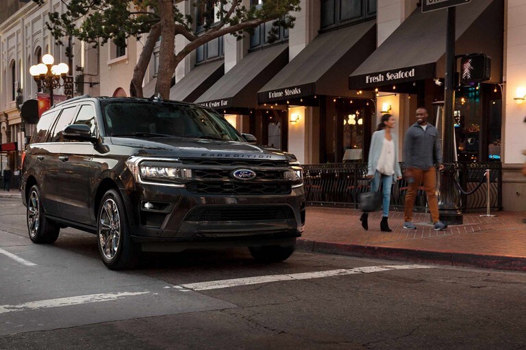 A 2024 Ford Expedition® Limited with the available Stealth Edition Package on a city street at night