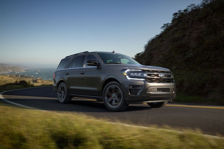 A 2024 Ford Expedition® on a winding hilly road with the ocean behind it