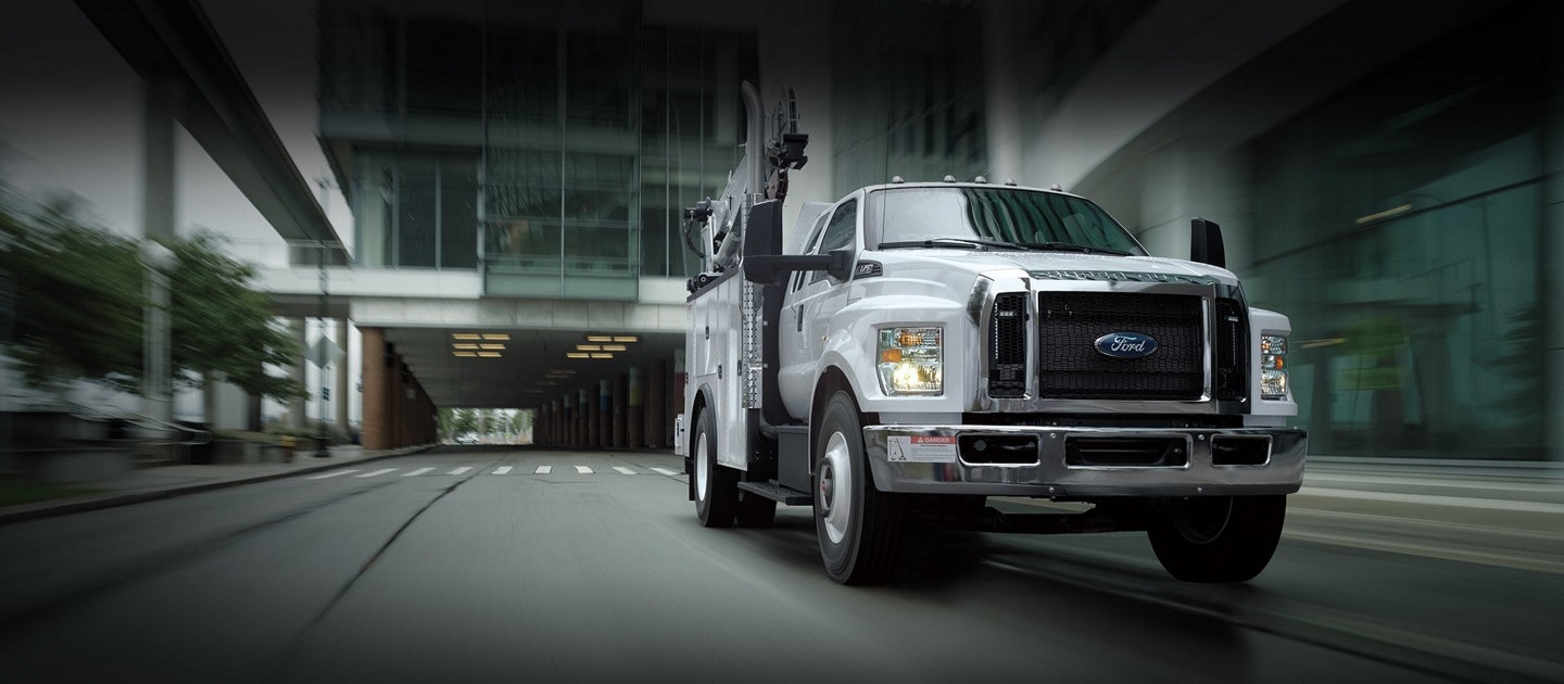 2023 Ford F-750 SuperCab with mechanic truck upfit in Oxford White being driven near large buildings