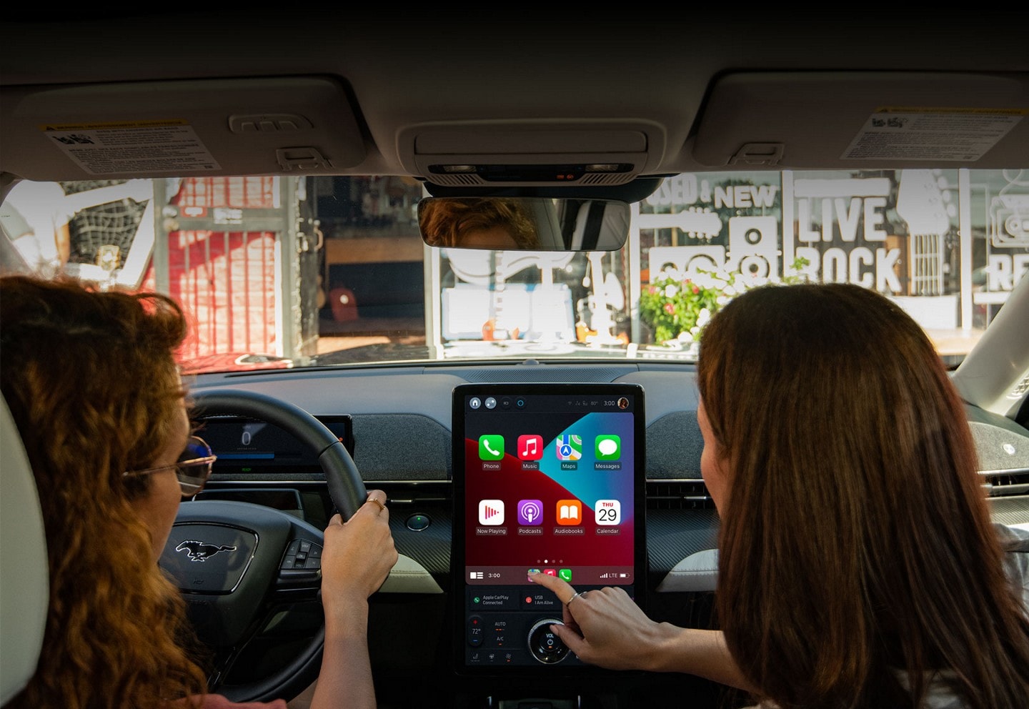 Interior of 2023 Mustang Mach-E® SUV with woman driving and passenger using the portrait touchscreen