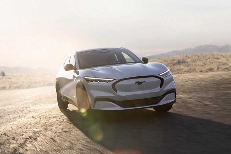 2023 Ford Mustang Mach-E® SUV being driven on a wide paved surface with the late afternoon sun creating lens flares