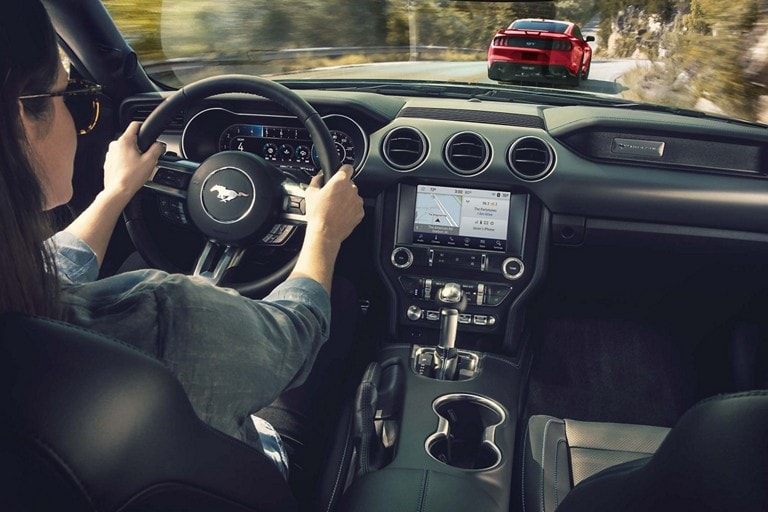 Interior of a 2023 Ford Mustang® model being driven showing touchscreen with SYNC® 3