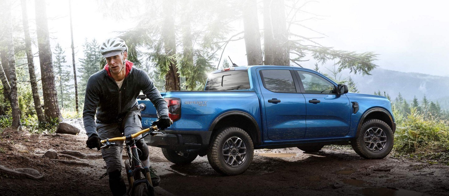 A 2024 Ford Ranger® XLT with sport appearance package parked on a muddy hill near a person on a mountain bike