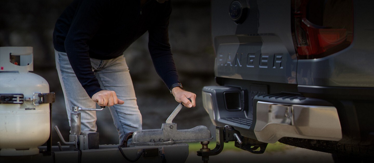 A person is hitching up their trailer to a 2024 Ford Ranger® in a scenic location