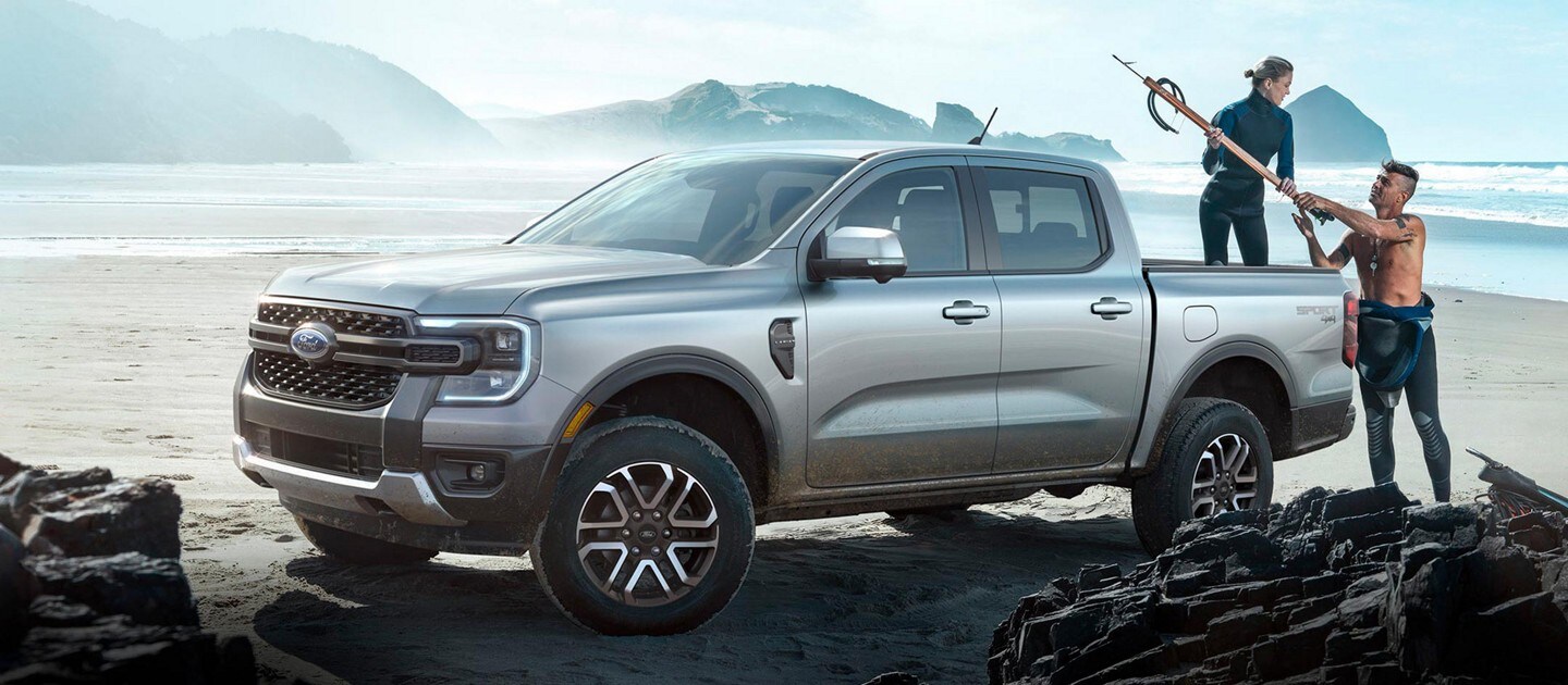 A 2024 Ford Ranger® model parked at a beach location with two people unloading gear