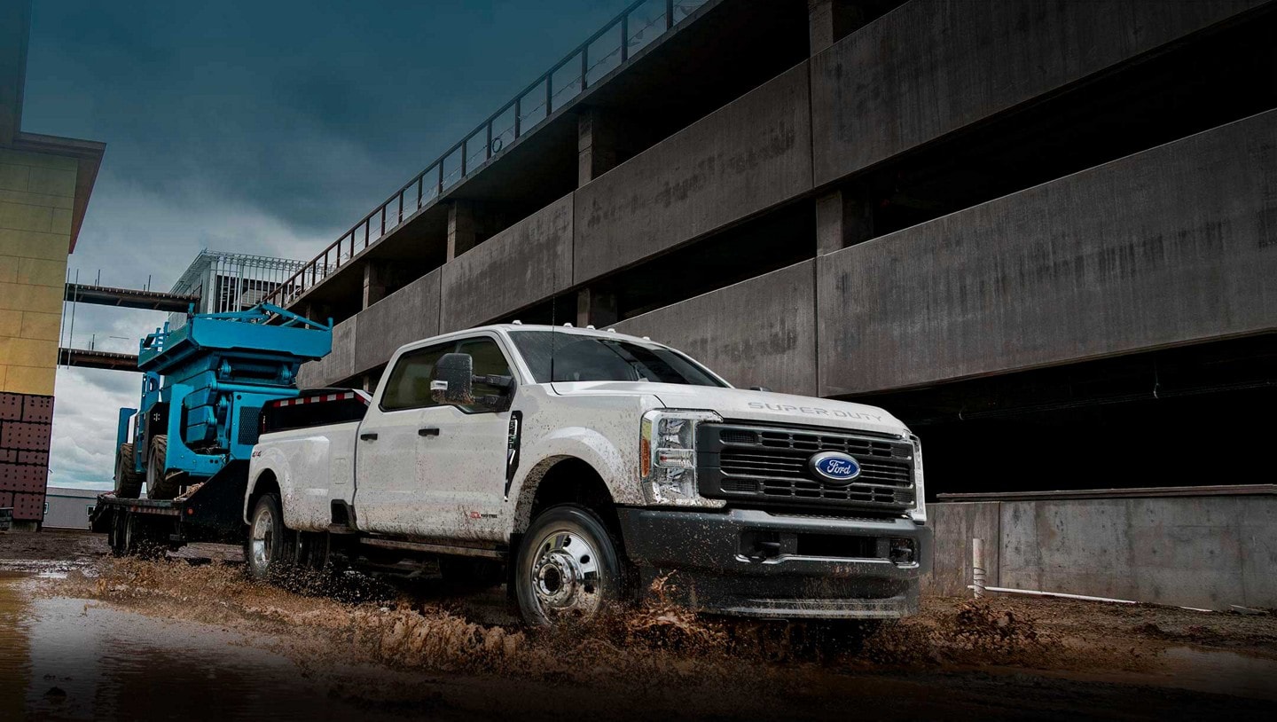 2023 Ford Super Duty® F-450® Super Crew Cab pulling a hydraulic lift on a trailer through muddy water