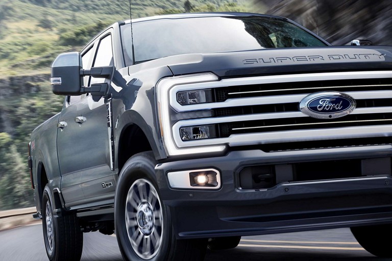 Front end of a 2025 Ford Super Duty® Platinum® TREMOR™ model in Oxford White being driven on a paved road