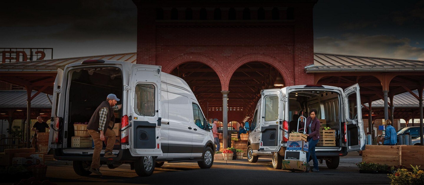 Two 2023 Ford Transit® Vans parked at a market unloading cargo