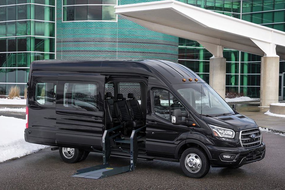 A black Ford Transit with its side door open showing a wheelchair platform lift.