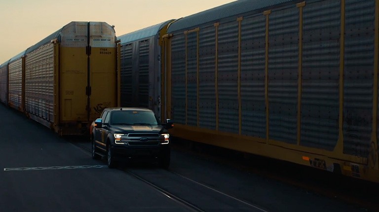 Two F-150 Lightning trucks at a train yard.