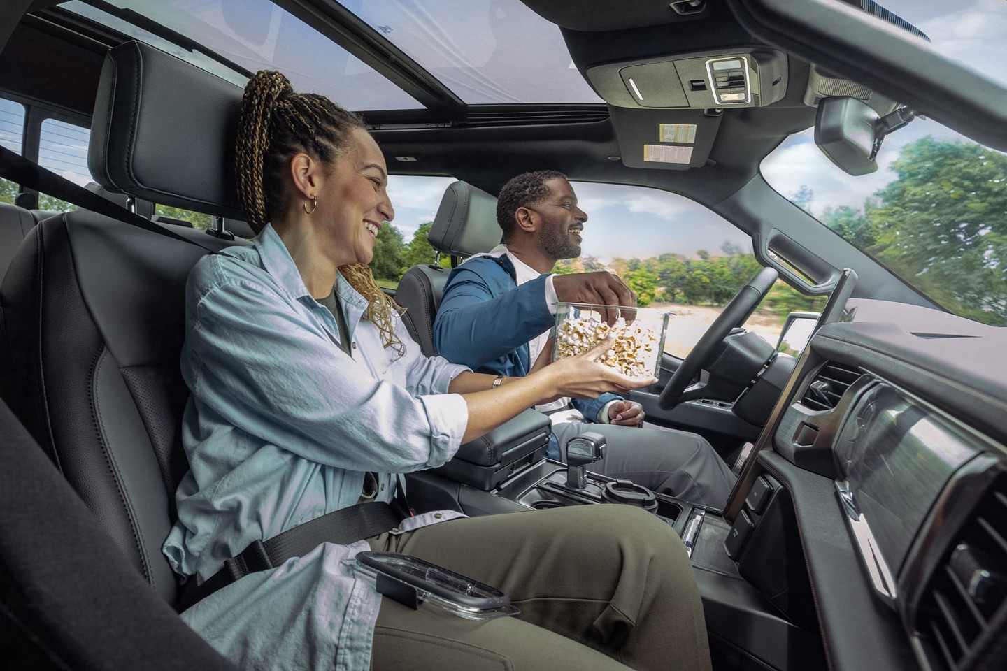 Two people share popcorn while their Ford vehicle drives hands-free.