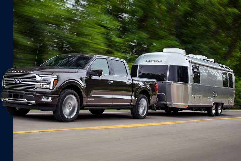 F-150 towing an RV on a two-lane highway.