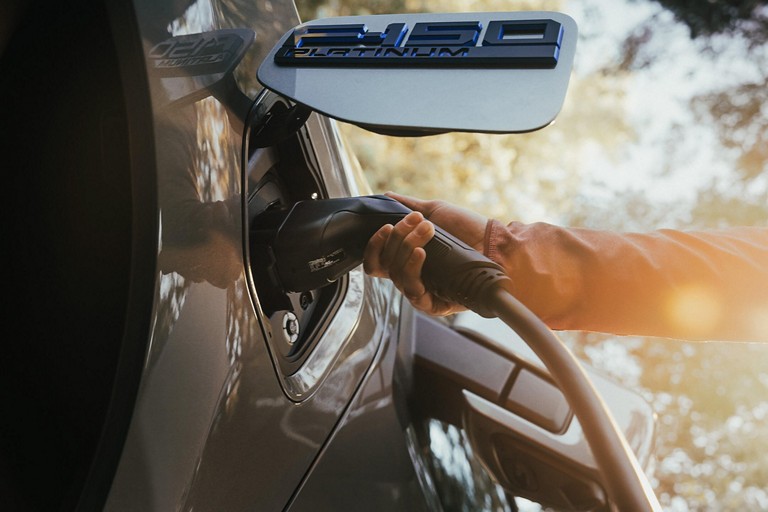 Person plugging a charging cable into an F-150 Lightning.