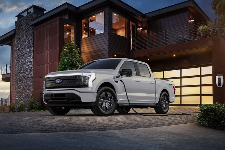 F-150 Lightning parked in front of a home and plugged into a Ford Charge Station Pro.