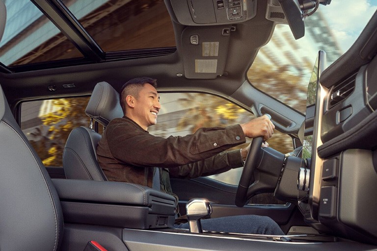 Interior shot of a man smiling as he drives a vehicle