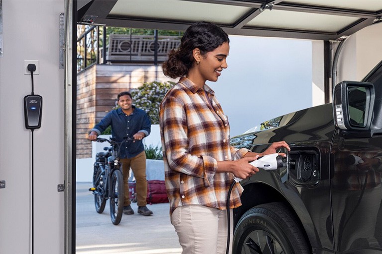 A woman plugs a charger into her vehicle