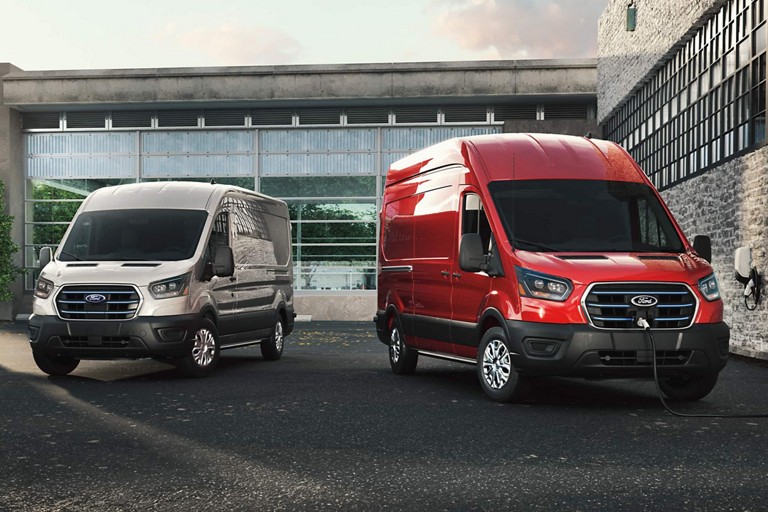 Two E-Transit vans parked outside of a commercial building.