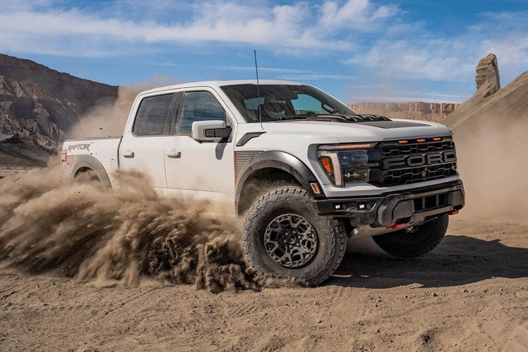 A Ford raptor truck driving through sand.