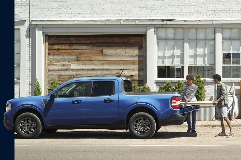Two people load a Ford Maverick truck bed.