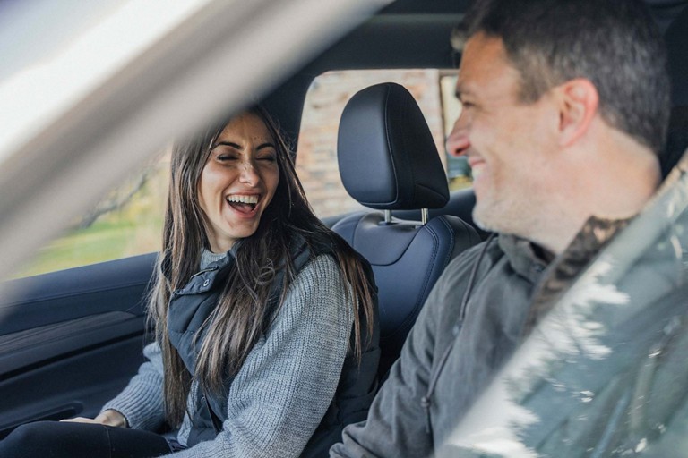 Driver and passenger laugh together in a Ford vehicle.