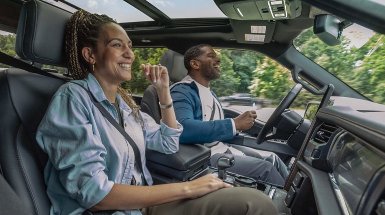 Two people laugh together as their vehicle drives hands free.